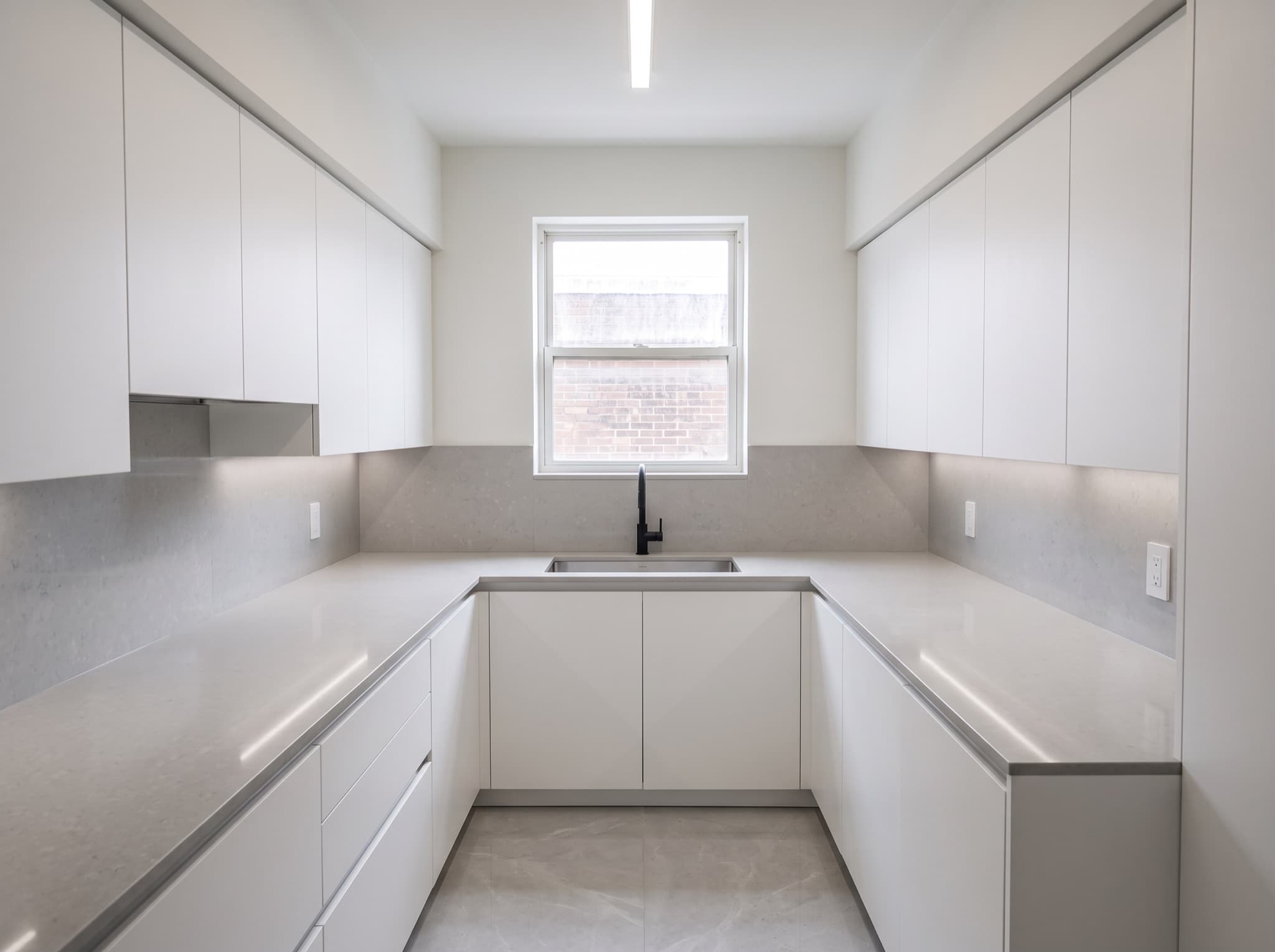 Small kitchen design AI comparison: a cramped U-shape kitchen opens up in pale full-height flat-panel cabinets — after, AI kitchen design result